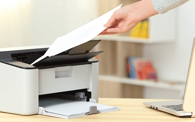 Image of a person holding a piece of paper and a printer