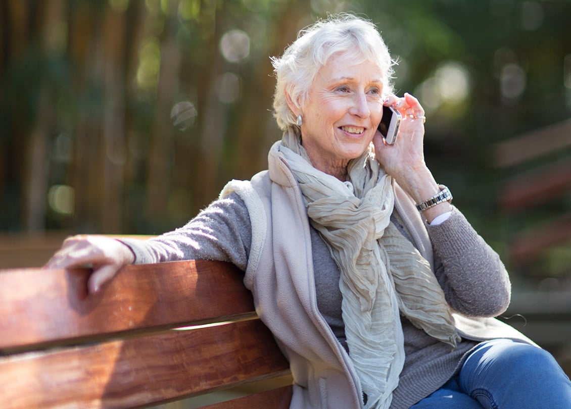 Image of woman—a Jakafi patient—talking on the phone, sitting on a park bench