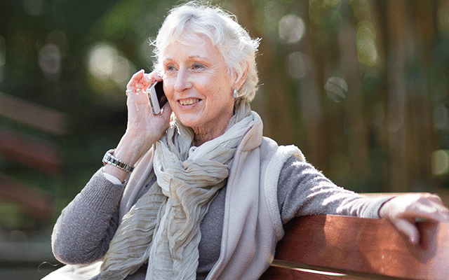 Image of woman – Jakafi patient – talking on the phone, sitting on a park bench