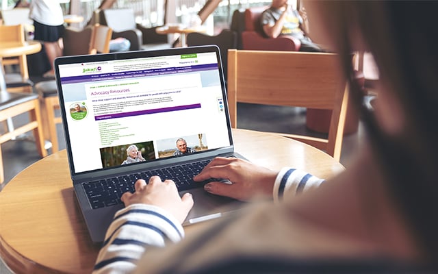 Image of a person sitting at a computer with the Jakafi website on the screen, sitting in a library type setting.